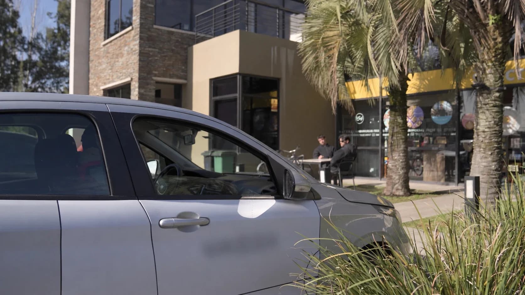 Auto ploteado estacionado frente a un local comercial con gente en la vereda