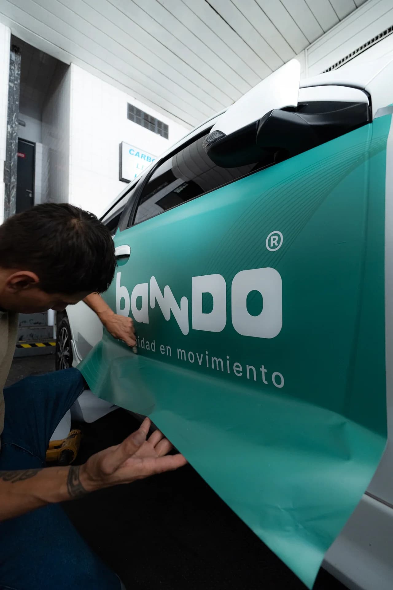 Instalador colocando el vinilo de Banndo en la puerta de un auto