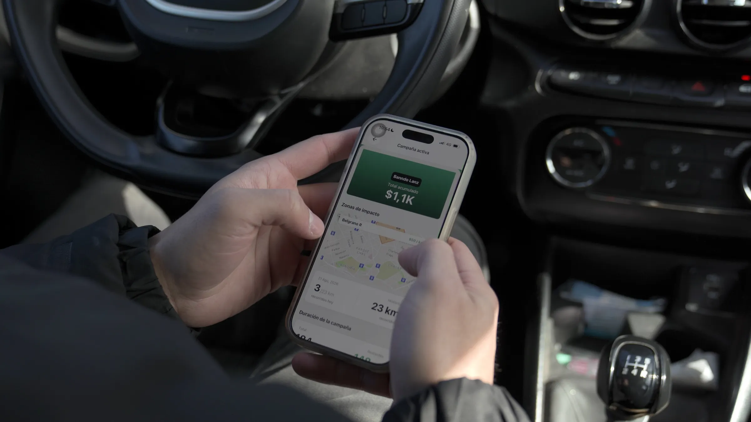 Conductor dentro de su auto revisando en la app de Banndo su campaña activa y sus zonas de impacto
